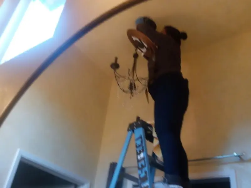 Electrician installing a chandelier in a Brent residence